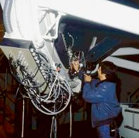Bill Binkert checks cables plugged into a large white telescope